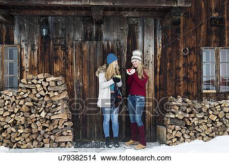 Two young female friends chatting outside wooden cabin View Large Photo Image Picture - Two young female friends chatting outside wooden cabin. Fotosearch