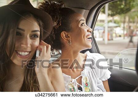 "Two young women in back of car, using smartphone" View Large Photo Image Stock Image - "Two young women in back of car, using smartphone". Fotosearch
