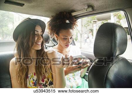 "Two young women in back of car, using smartphones" View Large Photo Image Stock Photography - "Two young women in back of car, using smartphones". Fotosearch