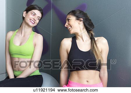 Two young women looking at each other and smiling in gym View Large Photo Image Picture - Two young women looking at each other and smiling in gym. Fotosearch