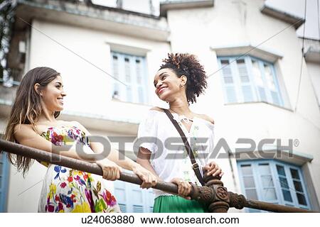 "Two young women standing by railings, low angle view" View Large Photo Image Stock Image - "Two young women standing by railings, low angle view". Fotosearch