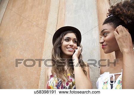 "Two young women standing together, using smartphone, close-up" View Large Photo Image Stock Image - "Two young women standing together, using smartphone, close-up". Fotosearch