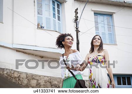 "Two young women, walking along street arm in arm" View Large Photo Image Stock Image - "Two young women, walking along street arm in arm". Fotosearch