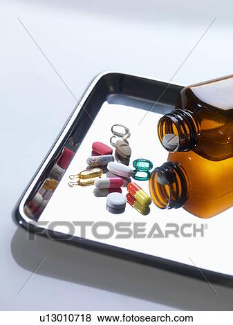 Variety of medical drugs pouring from pill bottle on surgical tray View Large Photo Image Stock Photo - Variety of medical drugs pouring from pill bottle on surgical tray. Fotosearch
