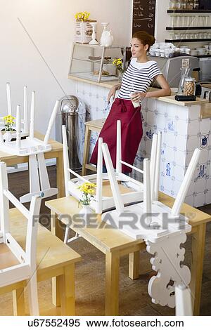 Stock Photography - Waitress in cafe leaning on counter. Fotosearch