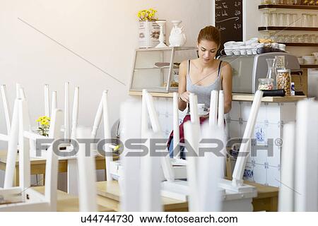 Stock Image - Waitress taking break in cafe. Fotosearch