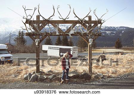 Stock Photograph - "Woman by archway with animal skulls, Girdwood, Anchorage, Alaska". Fotosearch