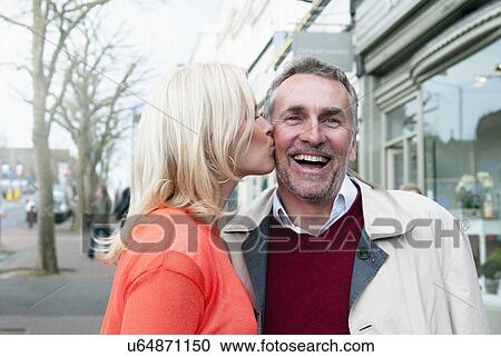 Woman kissing boyfriend on cheek on village street View Large Photo Image Stock Image - Woman kissing boyfriend on cheek on village street. Fotosearch