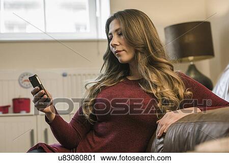 Woman relaxing at home with smartphone View Large Photo Image Stock Image - Woman relaxing at home with smartphone. Fotosearch
