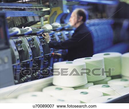 Stock Photo - Worker at weaving machine in factory. Fotosearch