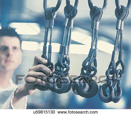 Worker holding metal hooks in steel mill View Large Photo Image Stock Image - Worker holding metal hooks in steel mill. Fotosearch