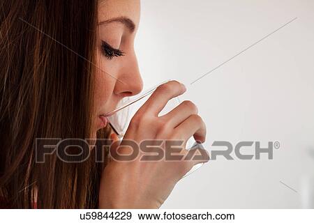 Stock Photo - Young adult woman sipping water from glass. Fotosearch