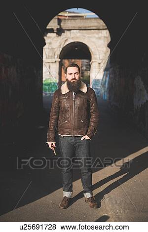 Stock Photo - Young bearded man by arch. Fotosearch