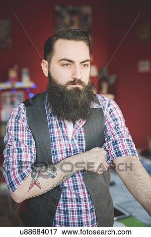 Young bearded man folding shirt sleeve View Large Photo Image Stock Photo - Young bearded man folding shirt sleeve. Fotosearch