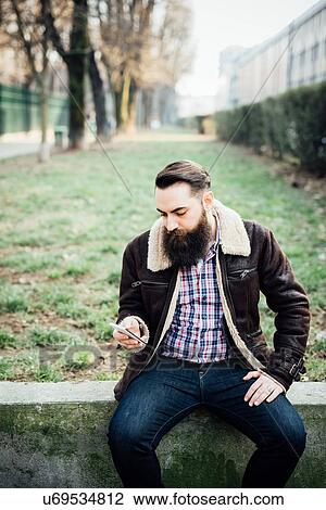 Stock Image - Young bearded man in park. Fotosearch