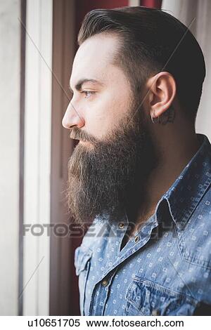 Young bearded man looking out of window View Large Photo Image Stock Photography - Young bearded man looking out of window. Fotosearch