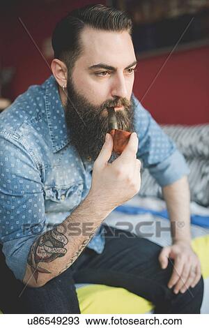 Young bearded man smoking pipe on bed View Large Photo Image Stock Image - Young bearded man smoking pipe on bed. Fotosearch
