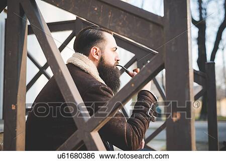 Young bearded man smoking pipe on steps View Large Photo Image Stock Photograph - Young bearded man smoking pipe on steps. Fotosearch