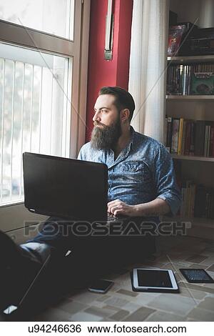 Young bearded man using laptop on floor View Large Photo Image Stock Photograph - Young bearded man using laptop on floor. Fotosearch
