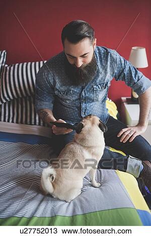 Young bearded man using smartphone on bed View Large Photo Image Stock Image - Young bearded man using smartphone on bed. Fotosearch