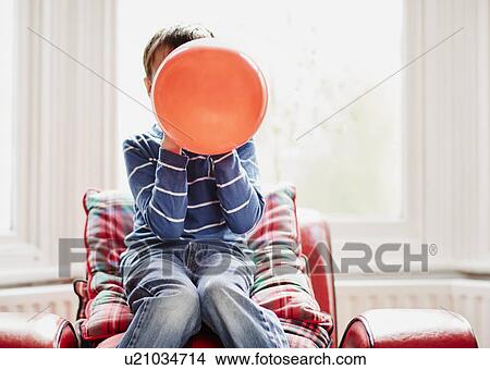 Young boy holding balloon in front of face View Large Photo Image Picture - Young boy holding balloon in front of face. Fotosearch