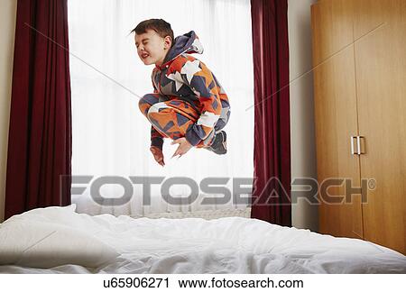 Young boy jumping on bed View Large Photo Image Stock Image - Young boy jumping on bed. Fotosearch