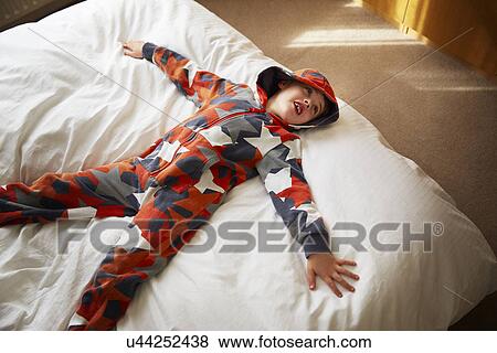 Young boy lying on bed View Large Photo Image Stock Photo - Young boy lying on bed. Fotosearch