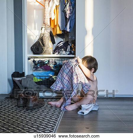 "Young boy sitting next to wardrobe, holding shirt" View Large Photo Image Stock Photograph - "Young boy sitting next to wardrobe, holding shirt". Fotosearch