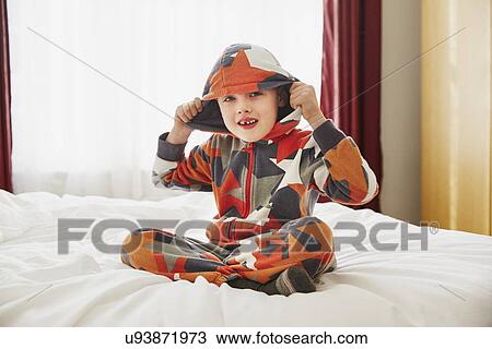 Young boy sitting on bed wearing hooded top View Large Photo Image Stock Image - Young boy sitting on bed wearing hooded top. Fotosearch