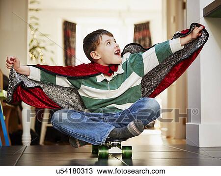 Young boy sitting on skateboard wearing cape View Large Photo Image Stock Image - Young boy sitting on skateboard wearing cape. Fotosearch