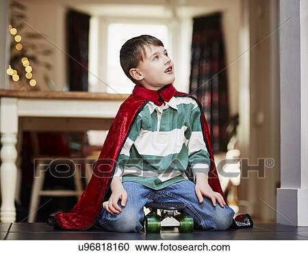Young boy sitting on skateboard wearing cape View Large Photo Image Stock Image - Young boy sitting on skateboard wearing cape. Fotosearch