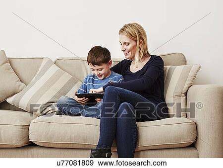 Stock Photo - Young boy using digital tablet with mother. Fotosearch