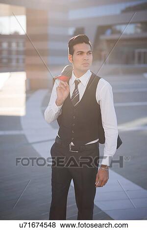 Young businessman carrying jacket View Large Photo Image Stock Photo - Young businessman carrying jacket. Fotosearch