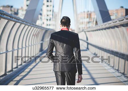 Stock Photo - Young businessman crossing bridge. Fotosearch