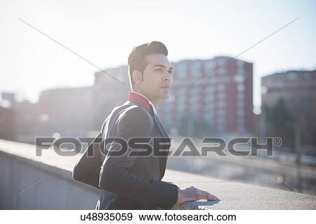 Young businessman looking over rooftop View Large Photo Image Stock Photo - Young businessman looking over rooftop. Fotosearch