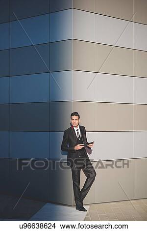 Young businessman using digital tablet against wall View Large Photo Image Picture - Young businessman using digital tablet against wall. Fotosearch