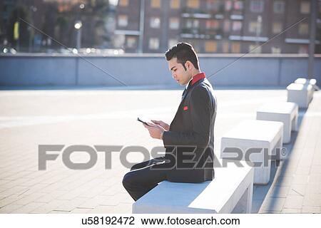 Young businessman using digital tablet on bench View Large Photo Image Stock Image - Young businessman using digital tablet on bench. Fotosearch