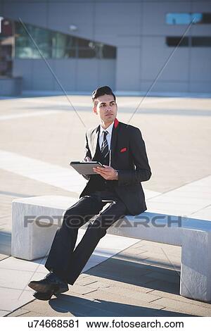 Young businessman using digital tablet on bench View Large Photo Image Stock Image - Young businessman using digital tablet on bench. Fotosearch