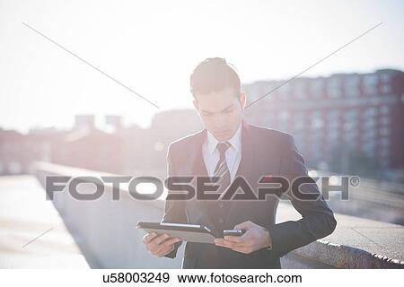 Young businessman using digital tablet on rooftop View Large Photo Image Stock Photo - Young businessman using digital tablet on rooftop. Fotosearch