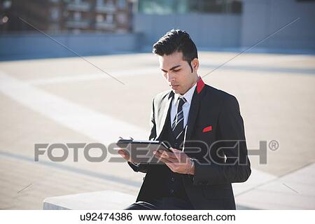 Young businessman using digital tablet on bench View Large Photo Image Stock Photograph - Young businessman using digital tablet on bench. Fotosearch