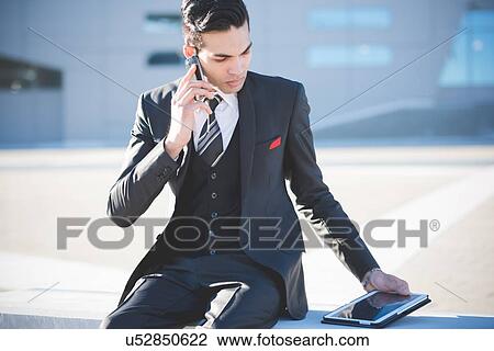 Young businessman using smartphone and digital tablet on bench View Large Photo Image Stock Image - Young businessman using smartphone and digital tablet on bench. Fotosearch