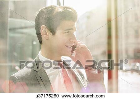 Stock Image - Young city businessman chatting on smartphone in doorway. Fotosearch