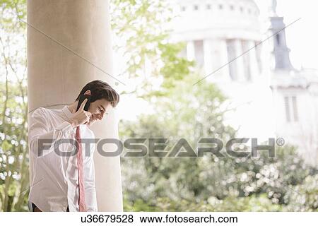 Young city businessman looking down chatting whilst chatting on smartphone View Large Photo Image Stock Photo - Young city businessman looking down chatting whilst chatting on smartphone. Fotosearch