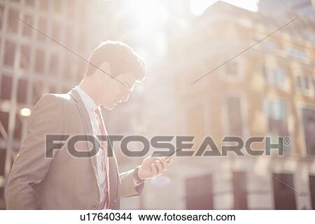 Young city businessman reading smartphone texts whilst walking View Large Photo Image Picture - Young city businessman reading smartphone texts whilst walking. Fotosearch