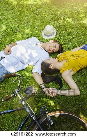 Young couple lying on grass holding hands View Large Photo Image Stock Image - Young couple lying on grass holding hands. Fotosearch