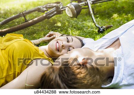 Young couple lying on grass holding hands View Large Photo Image Stock Photo - Young couple lying on grass holding hands. Fotosearch