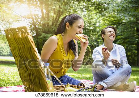 Young couple sitting eating picnic laughing View Large Photo Image Stock Photo - Young couple sitting eating picnic laughing. Fotosearch