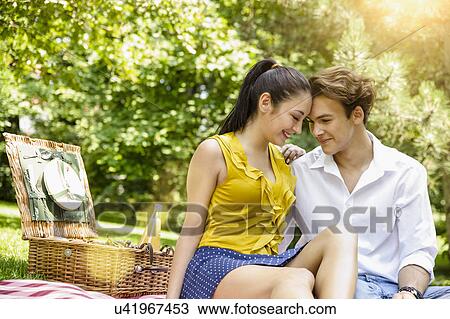 Stock Image - Young couple sitting together heads touching. Fotosearch