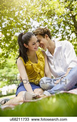 Stock Image - Young couple sitting together smiling. Fotosearch