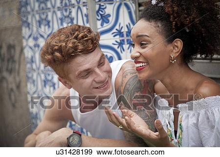 Stock Photo - "Young couple sitting together, laughing". Fotosearch